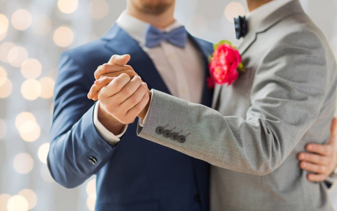 happy male gay couple holding hands and dancing